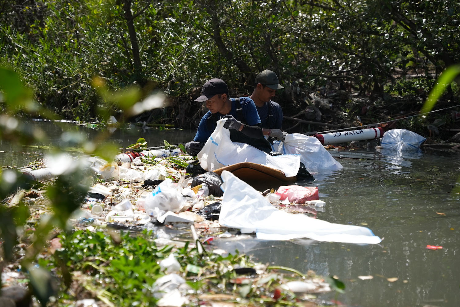 The Sungai Watch river warriors assess the mass of trash caught in one of the floating river barriers.