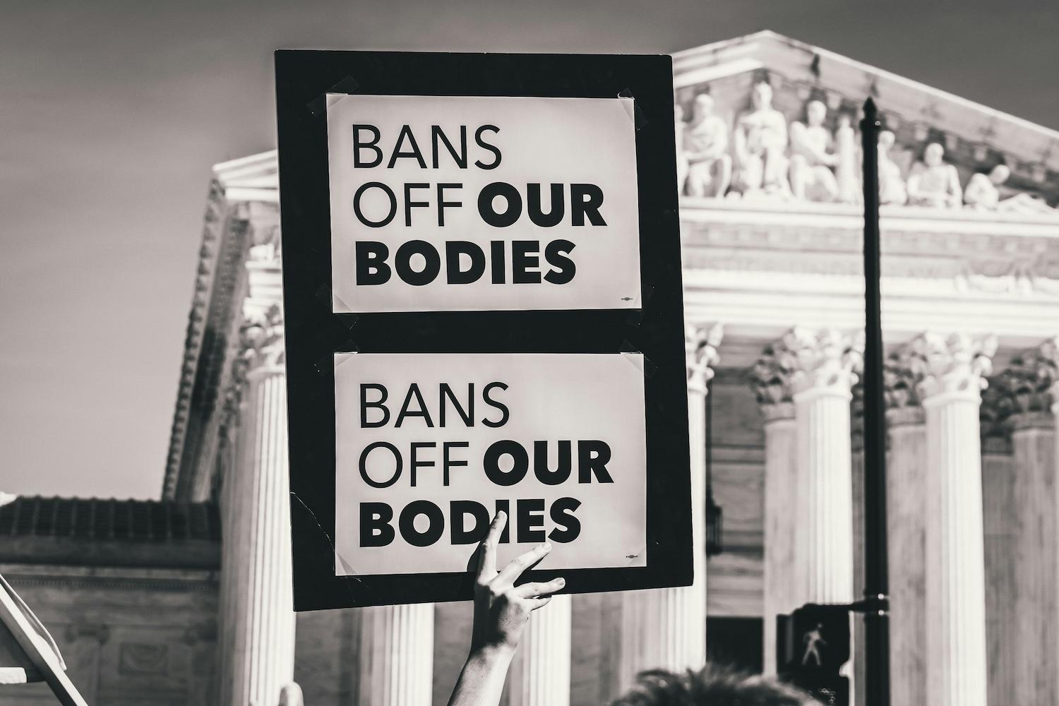 An activist holding a sign that reads, "Bans off our bodies." 