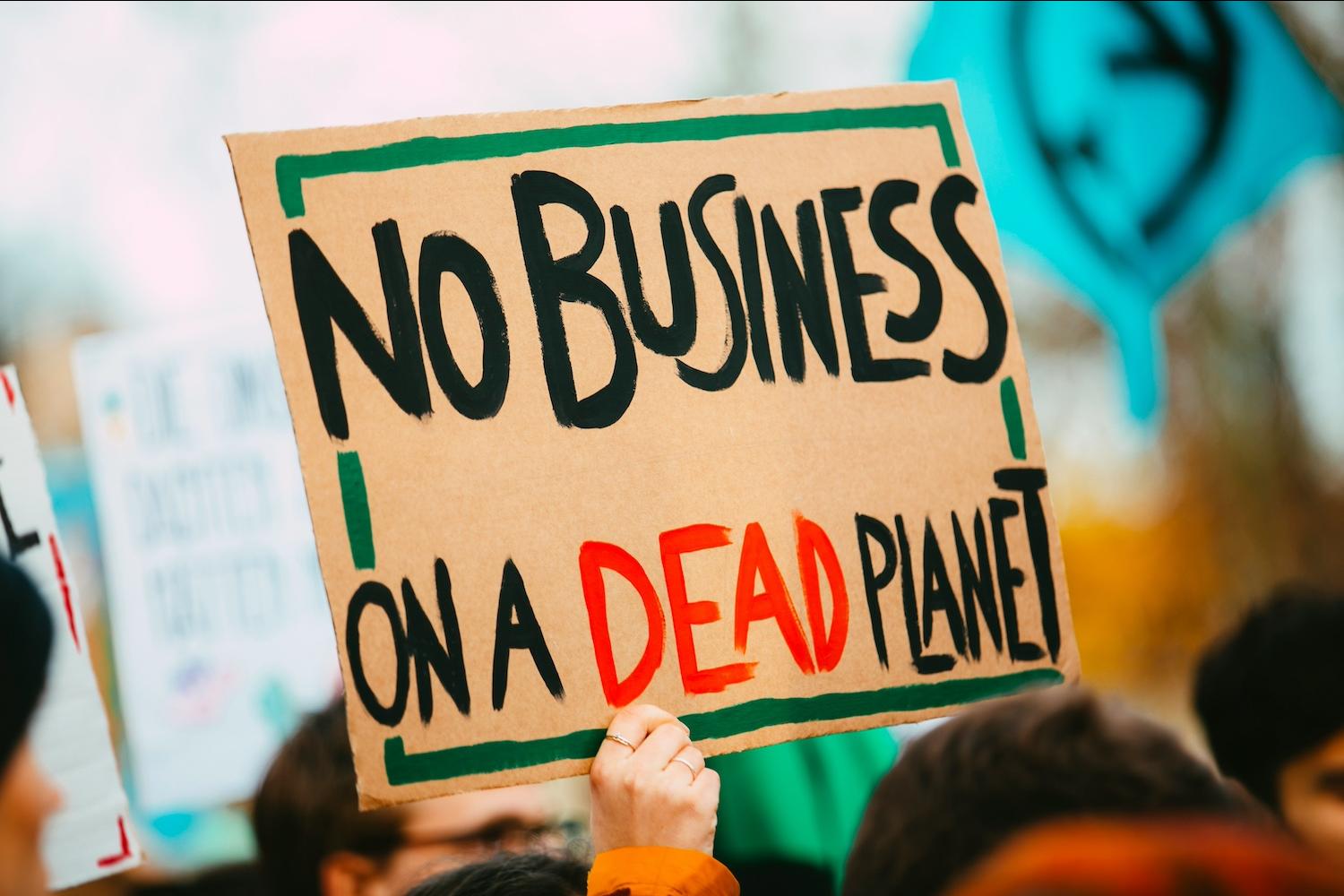 An activist with a sign that reads "No business on a dead planet." 