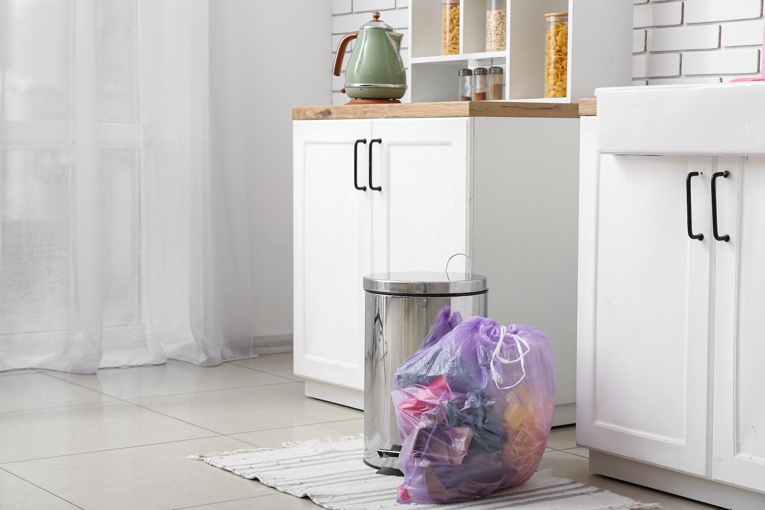 trash bag next to trash can in a kitchen - triplepundit waste audit