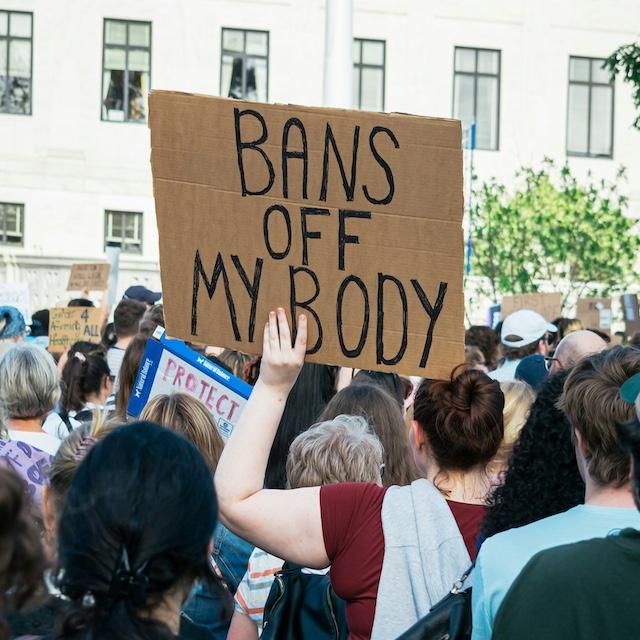 An activist holding a sign that reads, "Bans off my body." 