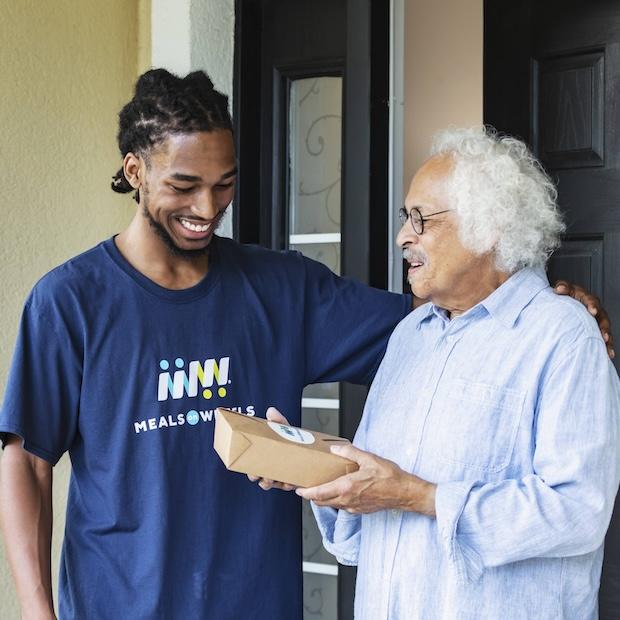meals on wheels volunteer hands meal to a senior