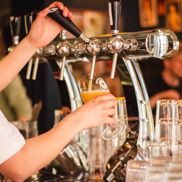 A bartender pouring a glass of beer. 