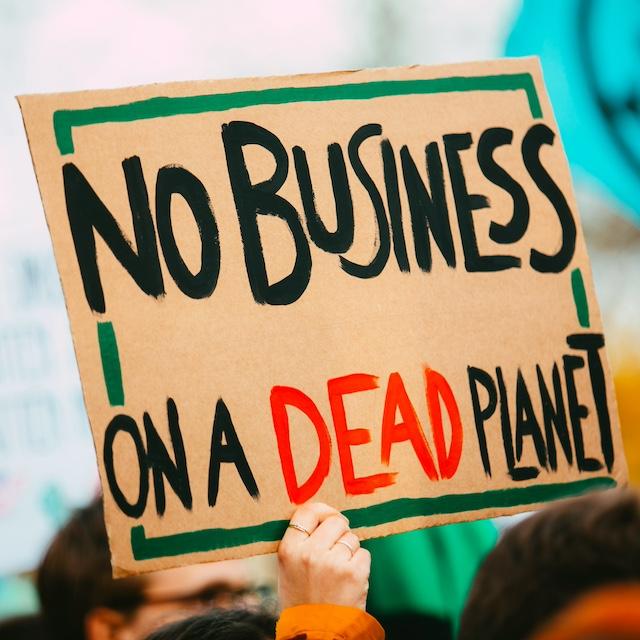 An activist with a sign that reads "No business on a dead planet." 