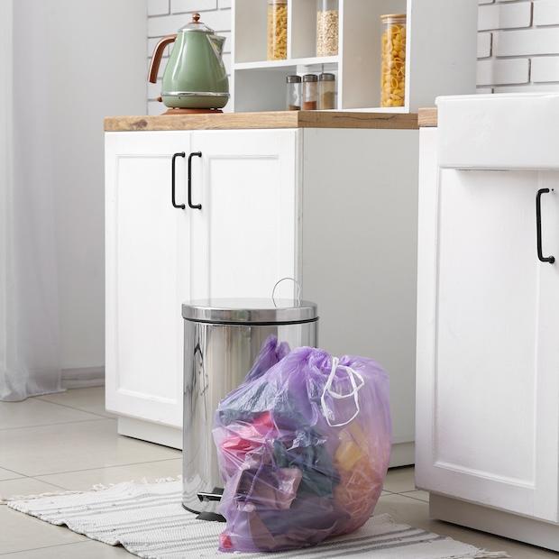 trash bag next to trash can in a kitchen - triplepundit waste audit