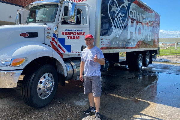 volunteer in front of truck giving thumbs up