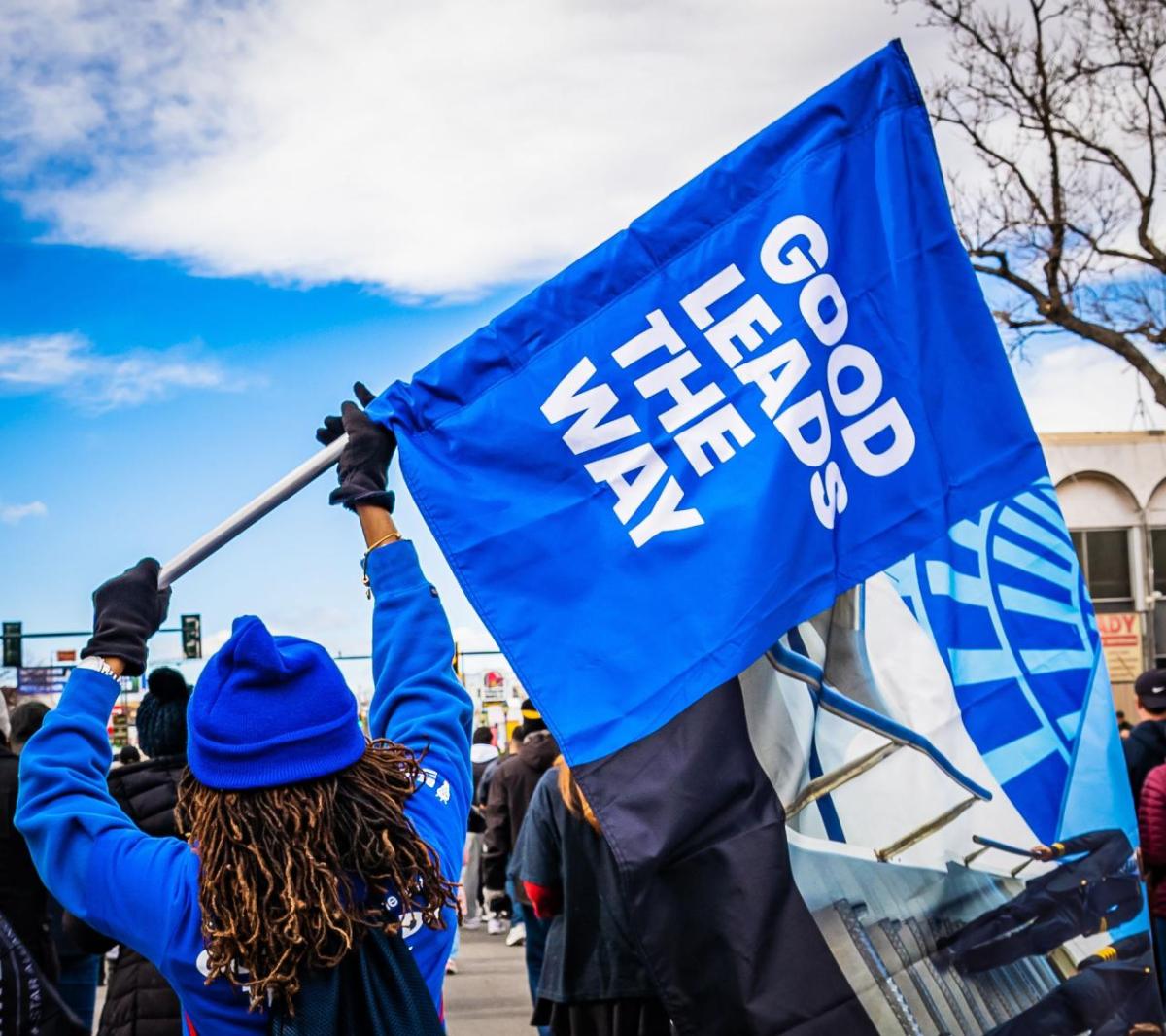 parade participant holds a flag saying "Good leads the way"