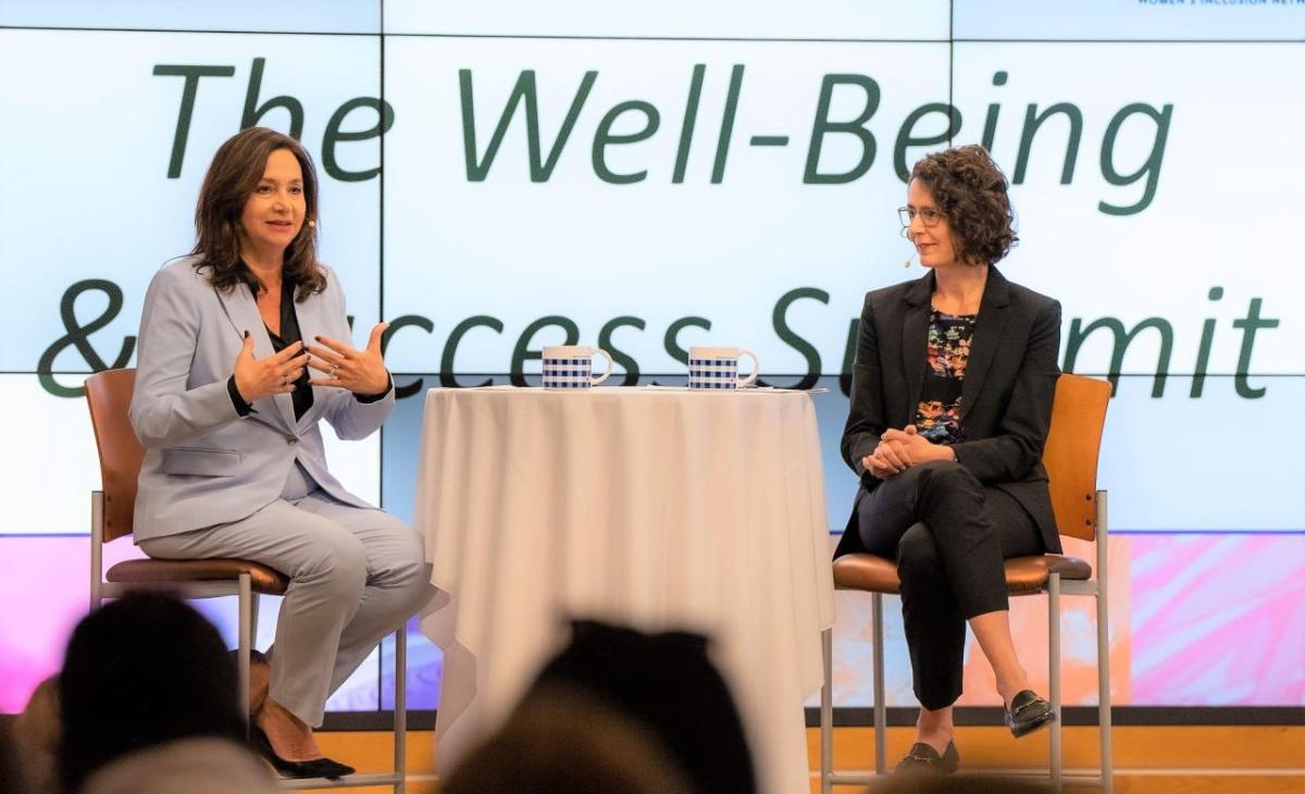 Two people sat on chairs talking on a stage at the Well-Being and Success Summit