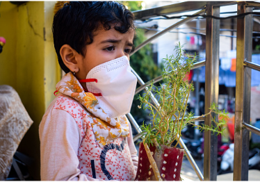 Masked child holding a plant