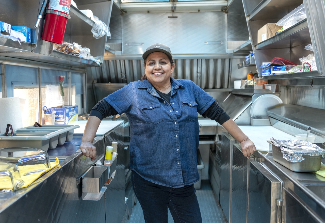 Smiling person standing in a small commercial kitchen