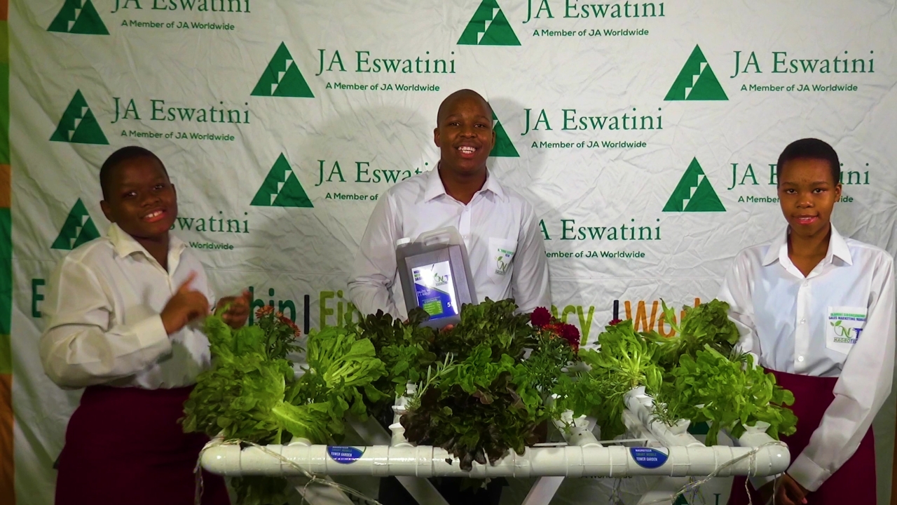Three students displaying a project that is growing many lettuce plants