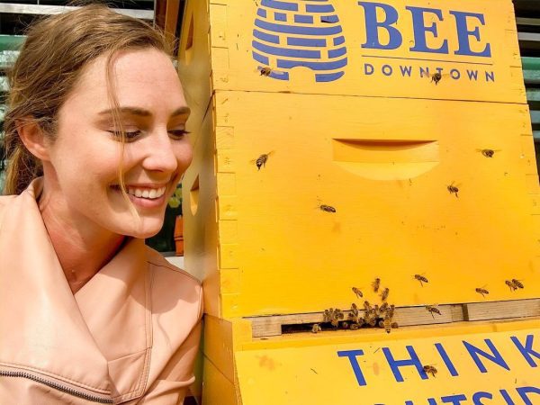 person next to a beehive