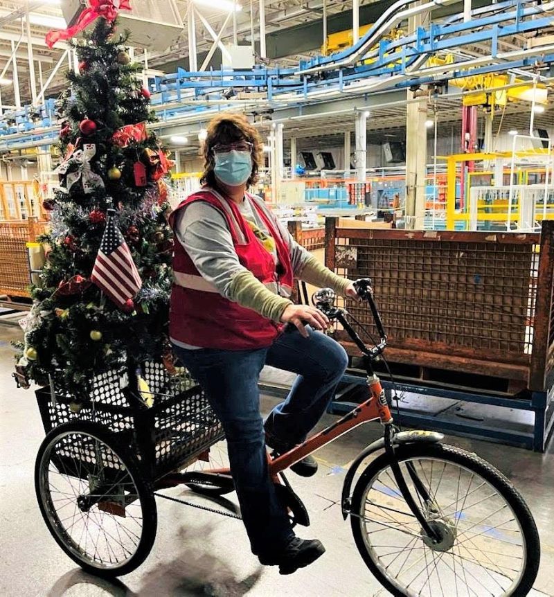 person riding tricycle with Christmas tree attached to the basket