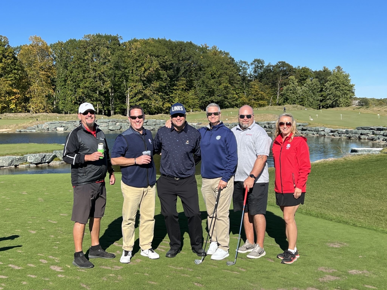 Group of golfers posing in front of pond