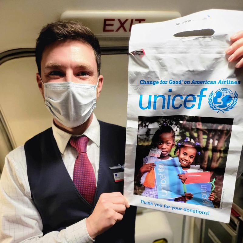 Flight attendant holds up a UNICEF donation bag