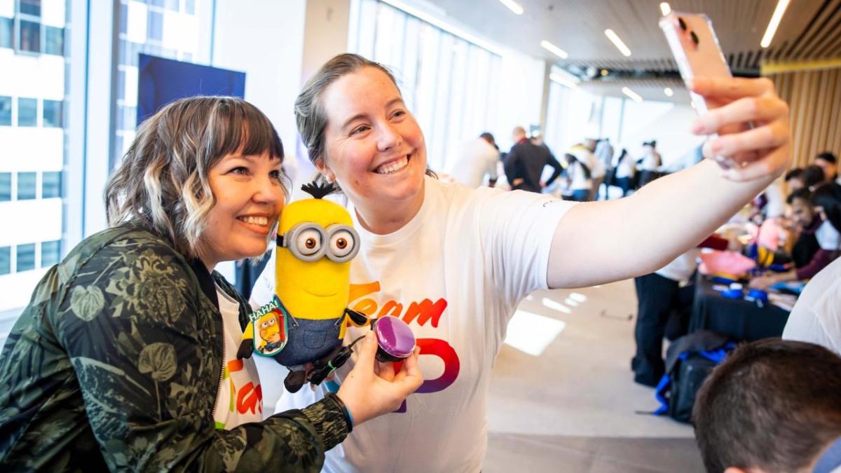 two volunteers taking a photo together whilst holding a toy