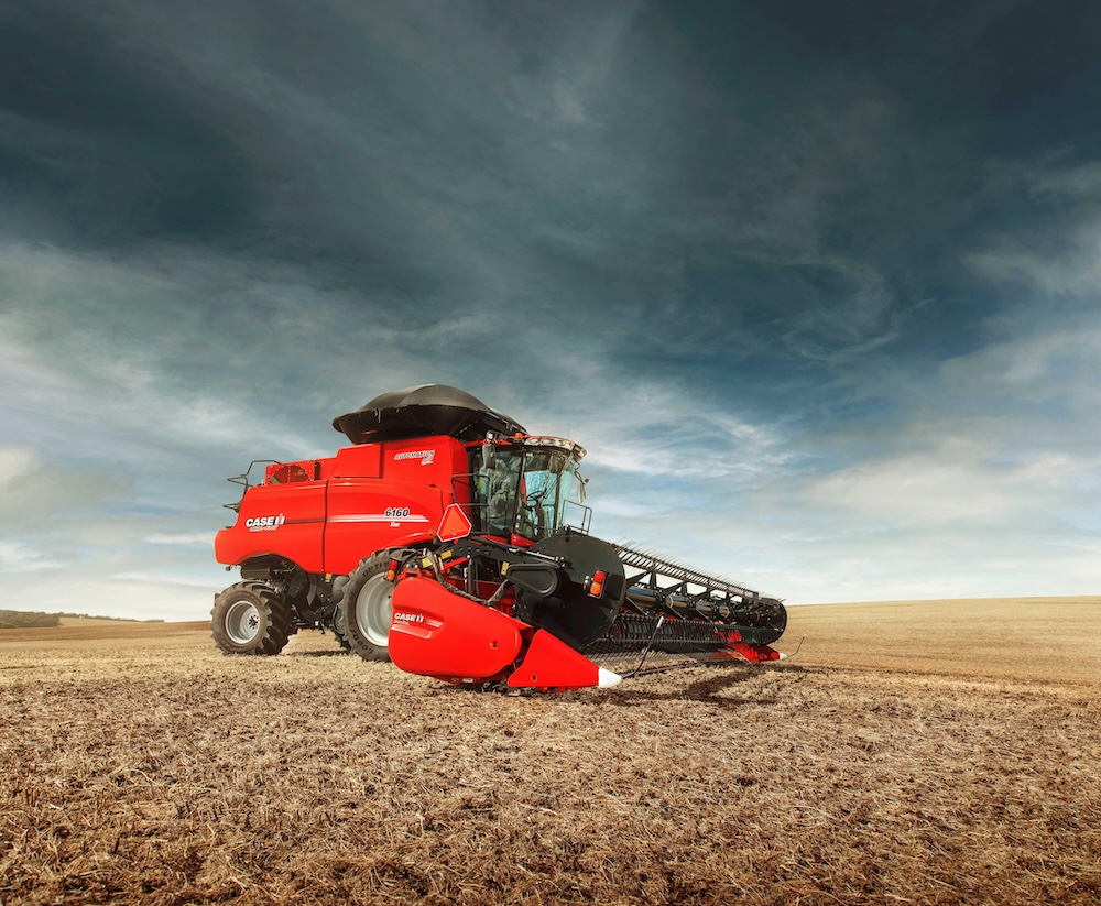 Red farm machine in a field with a dark sky