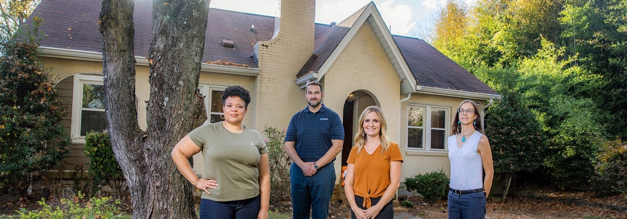 Image of four volunteers standing outside house