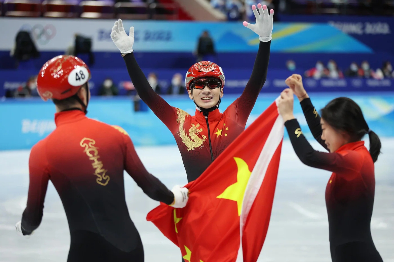three athletes hold the Chinese flag