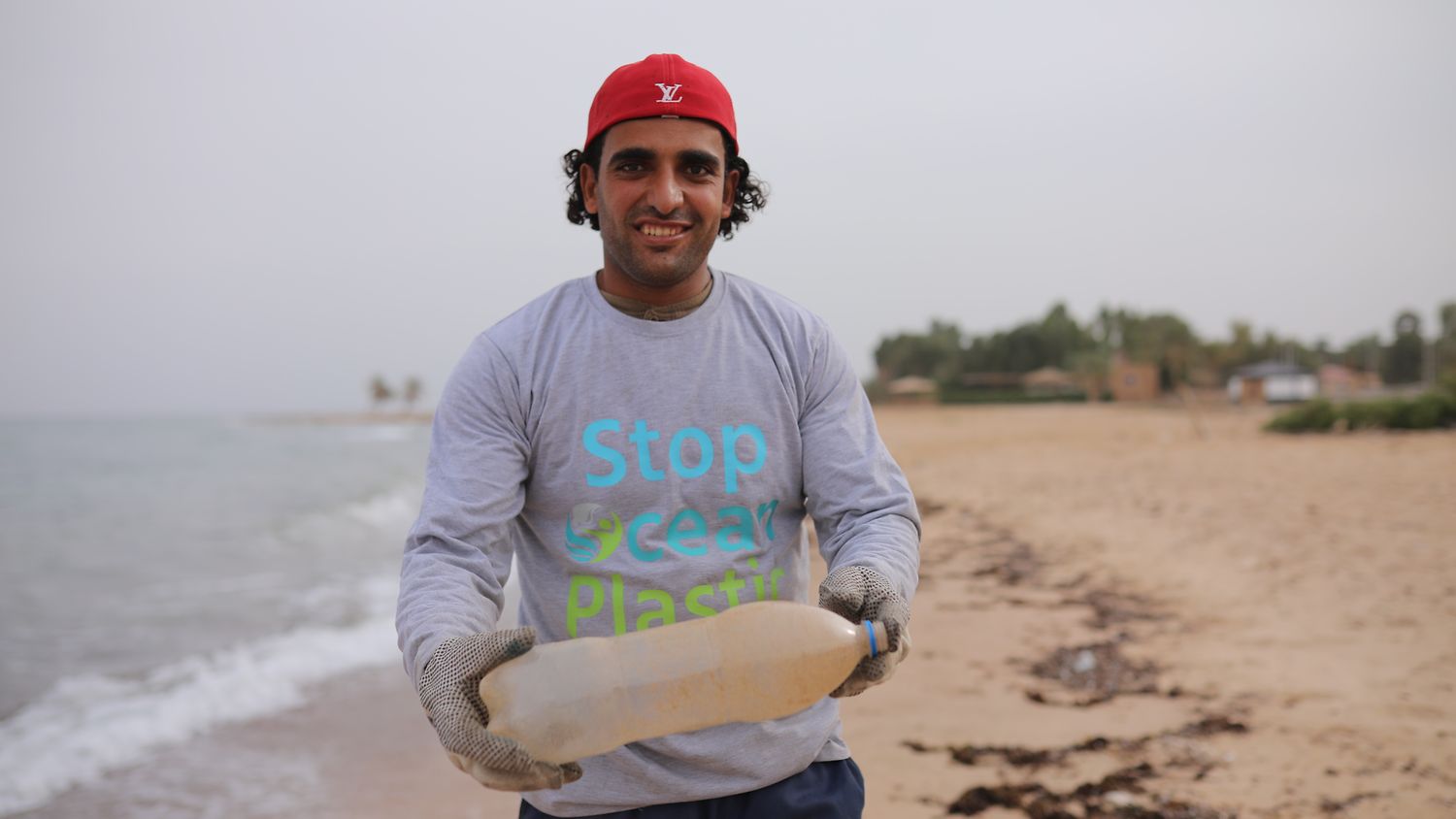 Person standing on beach holding a plastic bottle