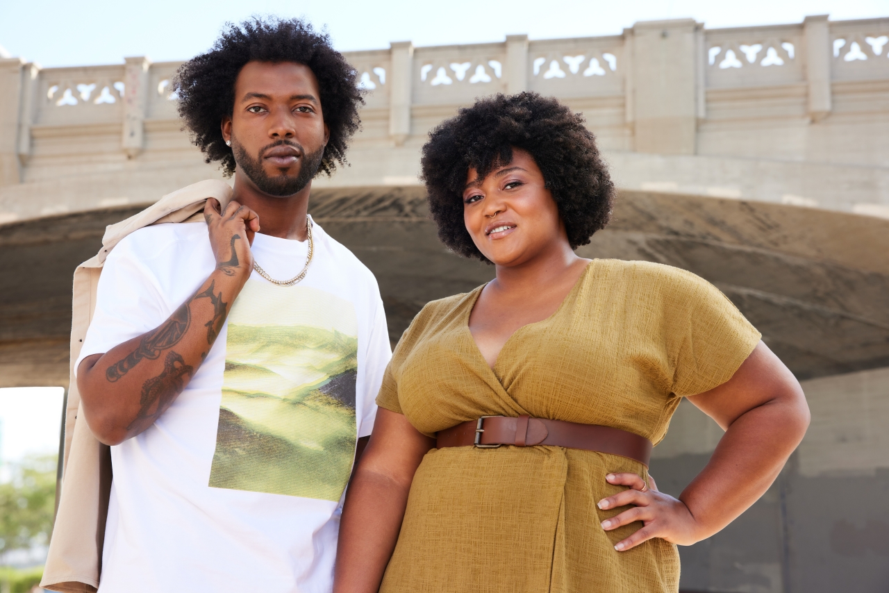 2 people stand in front of a bridge