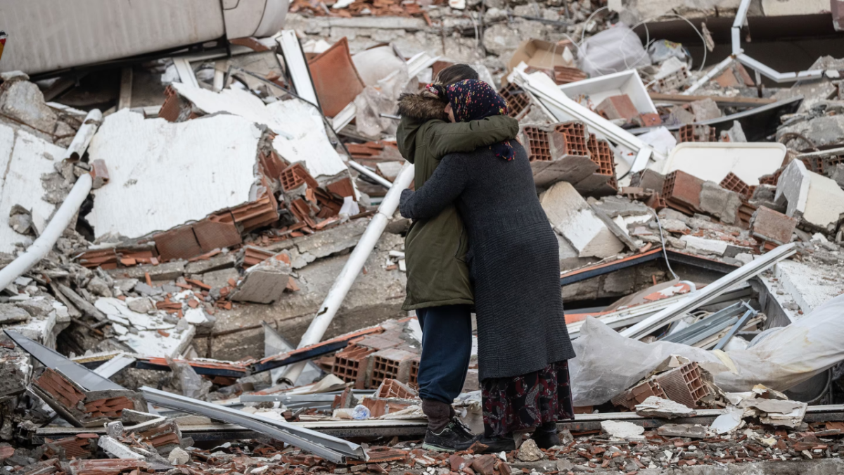 2 people hug amongst rubble