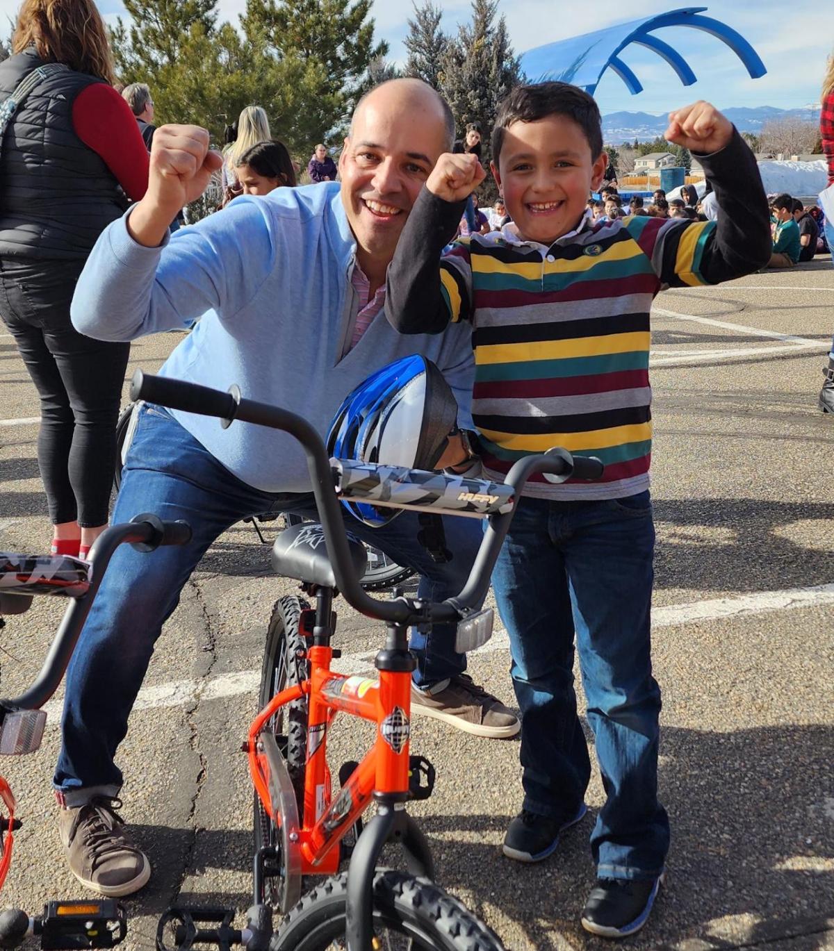 A man and a young boy pose with a bike.