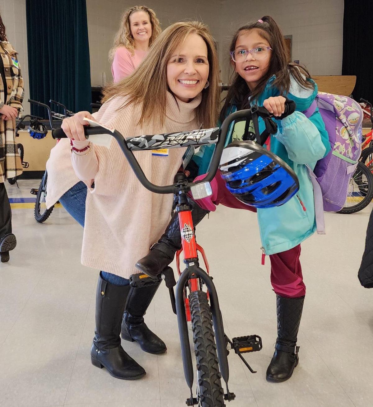 An Arrow employee poses with a little girl and a bike