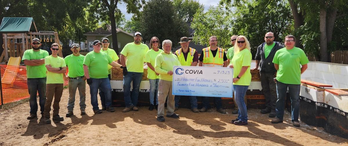 Front Holding Check: (L) Curtis Miller, Habitat for Humanity Construction Supervisor (R) Anna Meyer, Covia Office Administrator     Back Row: Covia employees (L to R): Tyler Betthauser, Logan Rohn, Jesse Rinehart, Chad Storkel, Nick DeHaan, Jered Iverson, Beth Kirchner, Russ Robitaille, LeRoy Olson, Riley Layton, Lee Peterson & Derek Brown
