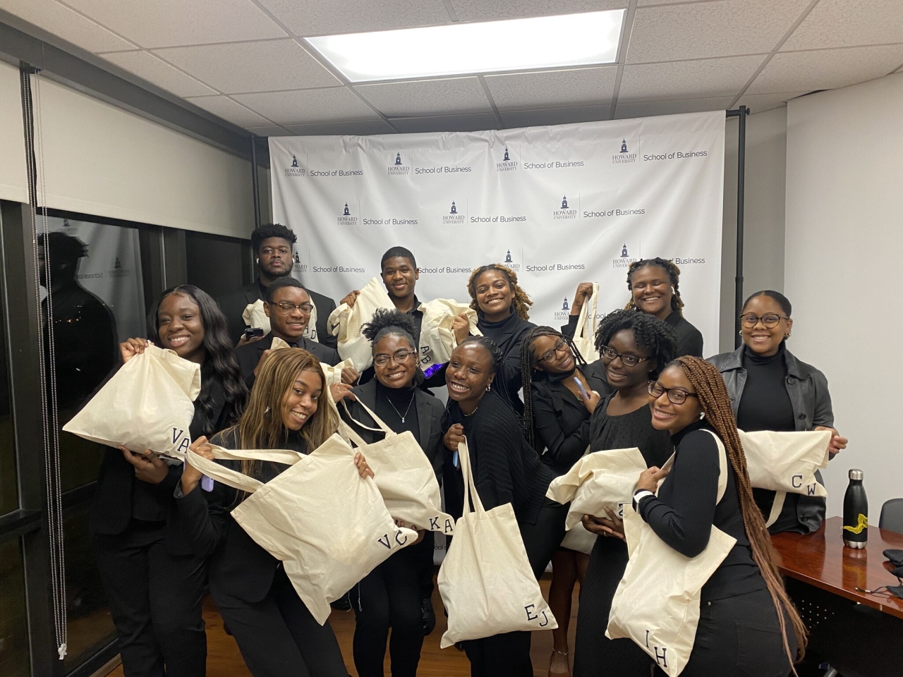 A group of M·A·C 21 CAP students holding matching tote bags