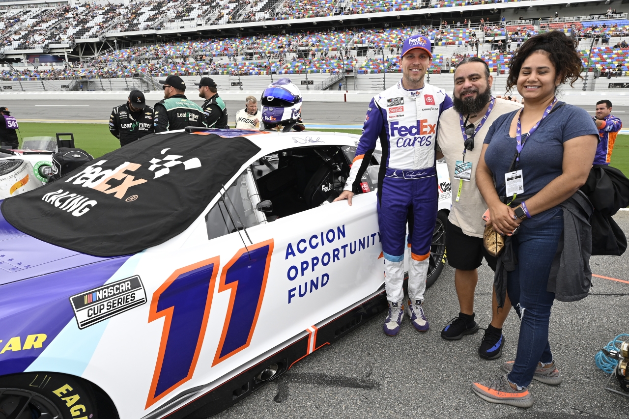 Mayra Hernandez, Jesse Iniguez and Denny Hamlin stand next to the FedEx 11 race car