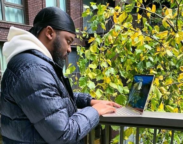 Jeremiah on a balcony writing on laptop