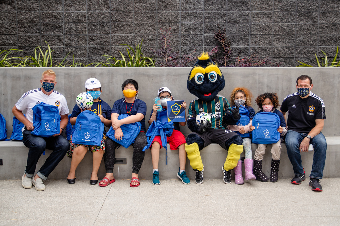 LA Galaxy First Team Goalkeeping Coach and LA Galaxy Legend Kevin Hartman (left), LA Galaxy Broadcaster Joe Tutino (right) and LA Galaxy mascot Cozmo congratulate youth participants from Little Tokyo Service Center after “breaking in” their new soccer equipment and LA Galaxy swag at the new Terasaki Budokan complex in downtown Los Angeles on May 10 2021