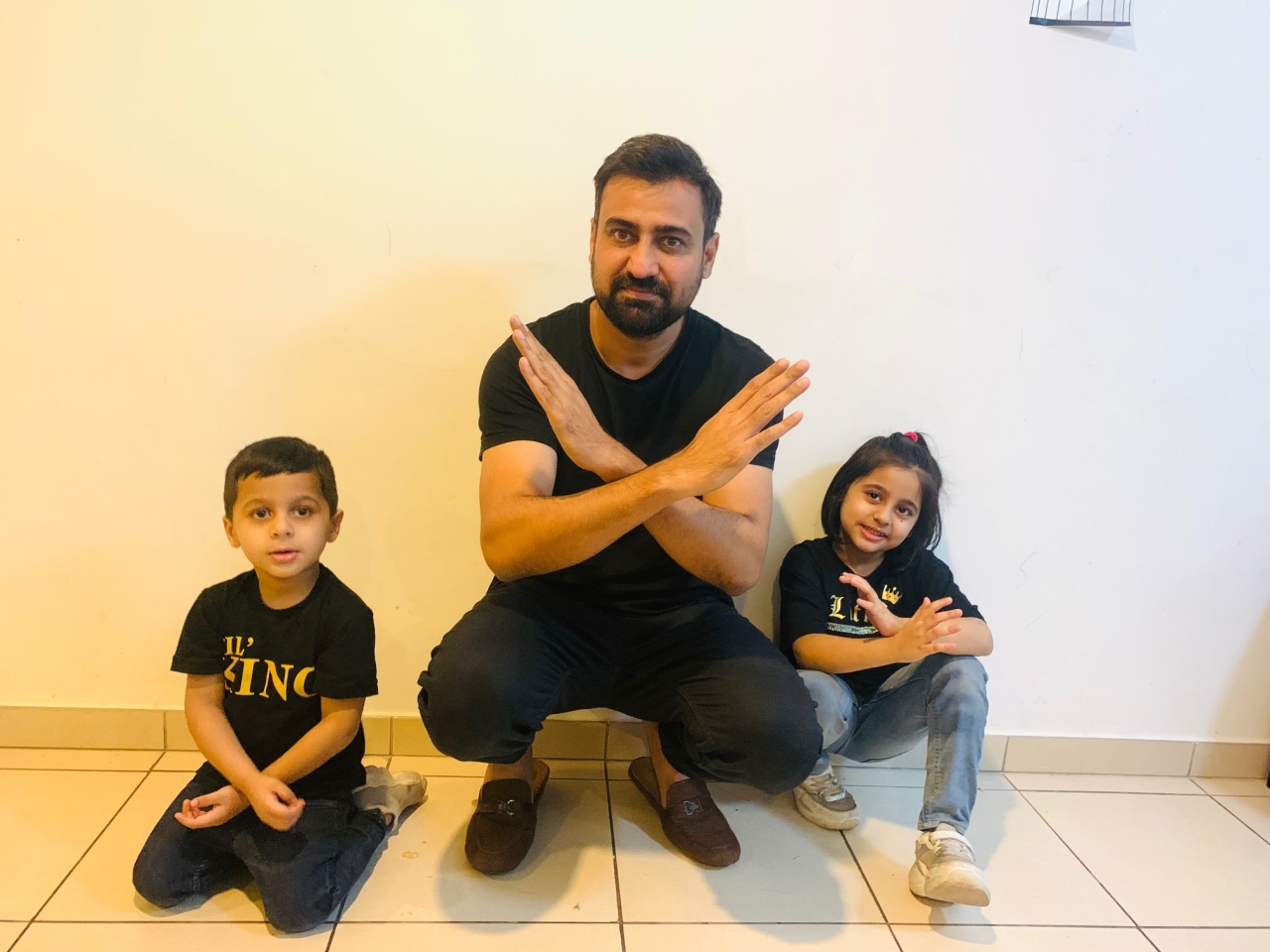 Man and two children in black t-shirts crossing their arms