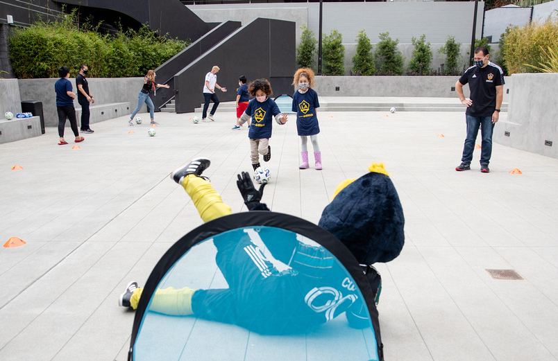 Youth participants from Little Tokyo Service Center test out the newly donated soccer equipment from the LA Galaxy with club mascot Cozmo at the new Terasaki Budokan complex in downtown Los Angeles on May 10 2021