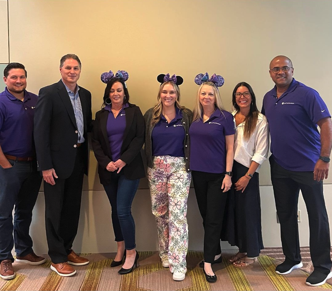7 people standing inside together wearing purple, three with purple mouse ears