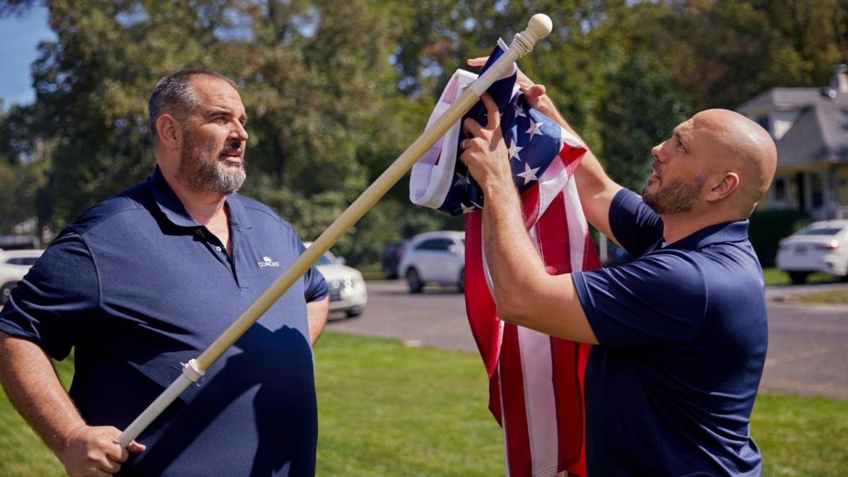 two people putting up American flag