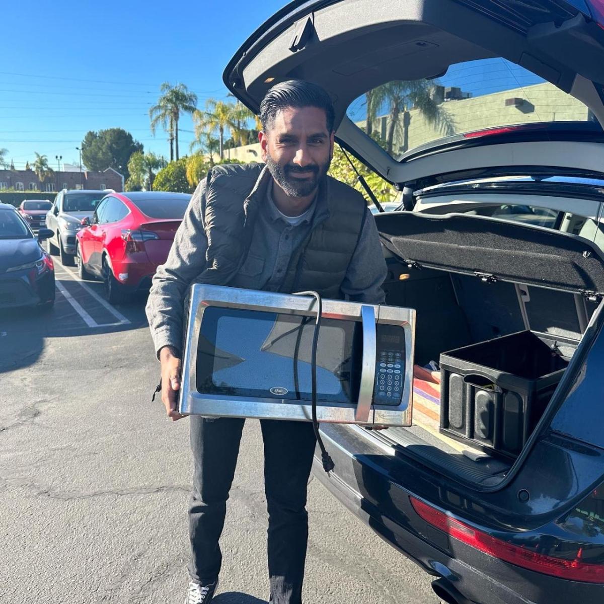 Man holding microwave in parking lot