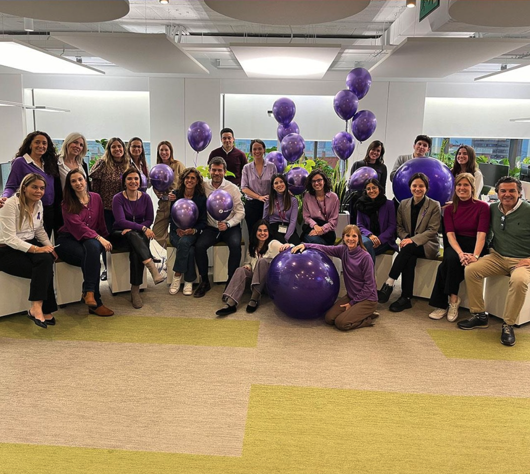 A group of people inside with purple balloons and a purple yoga ball