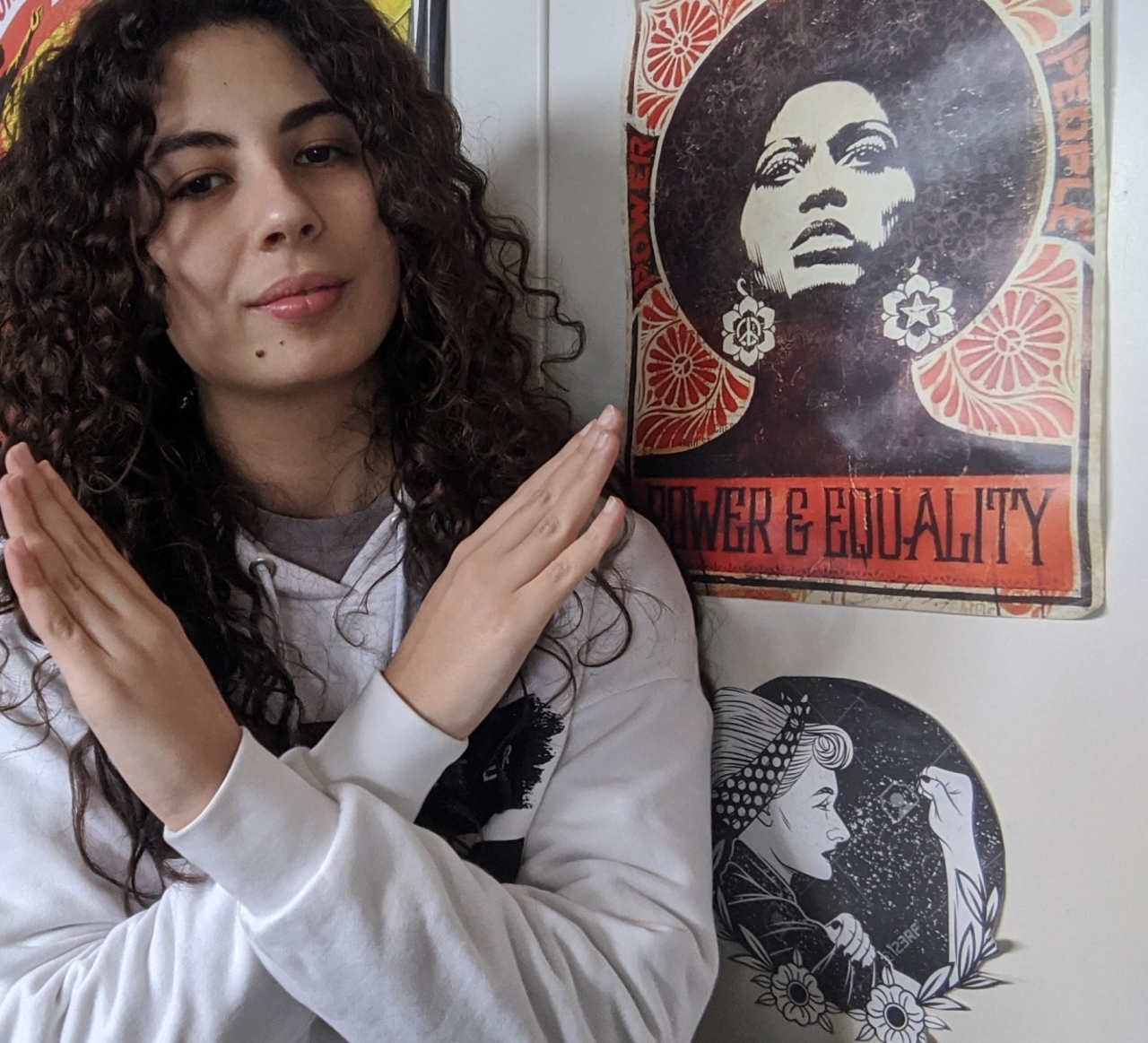 Woman standing next to a poster that reads Power & Equality, crossing her arms