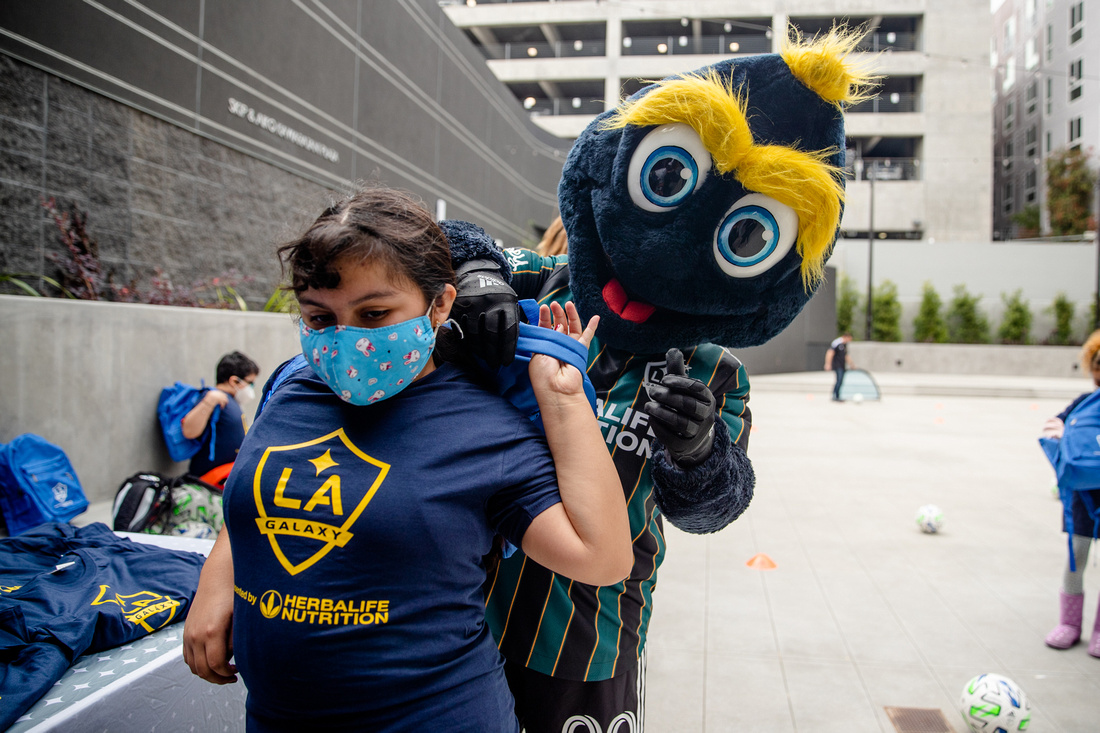 LA Galaxy mascot Cozmo passes out club swag to youth participants from Little Tokyo Service Center during a soccer equipment drop-off at the new Terasaki Budokan complex in downtown Los Angeles on May 10 2021