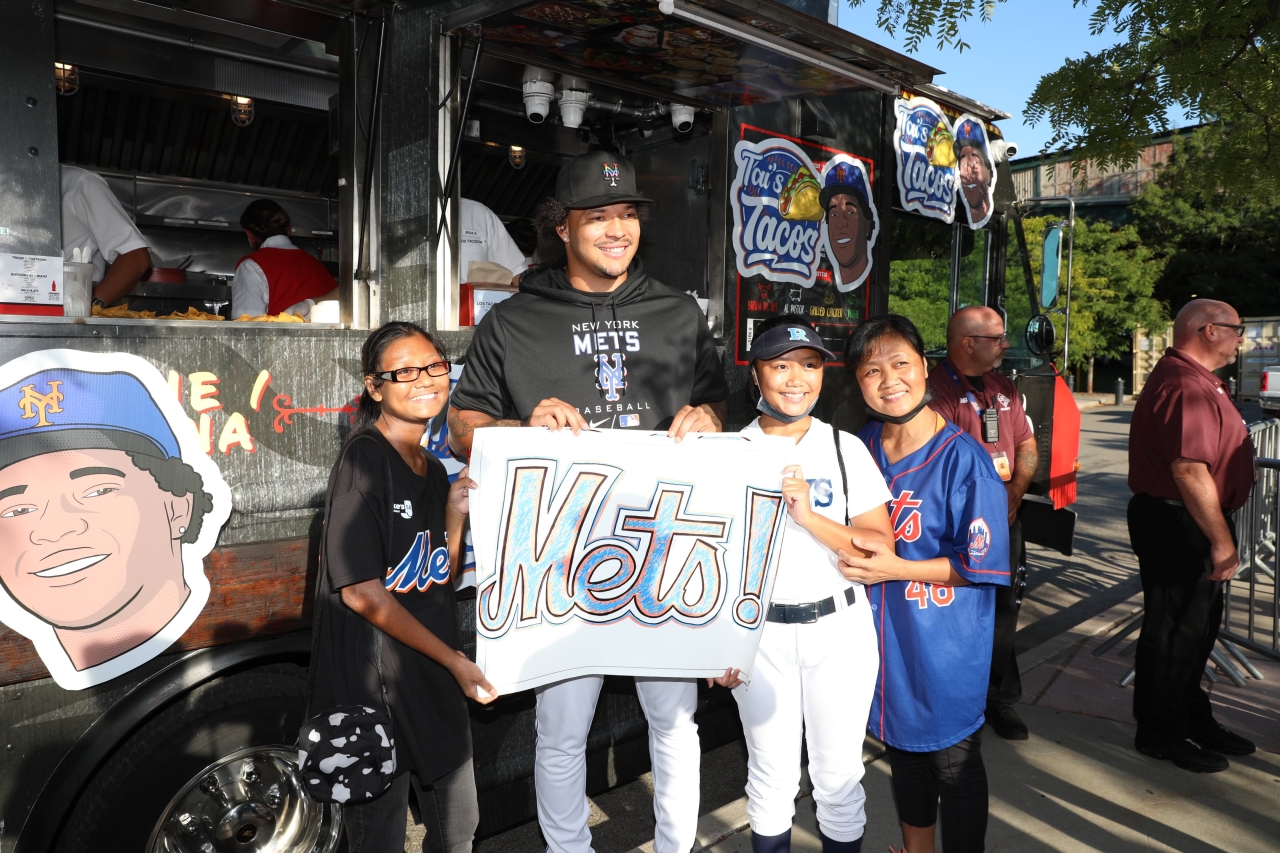 kids and one adult posing next to Tai's Taco Truck holding a Mets! sign