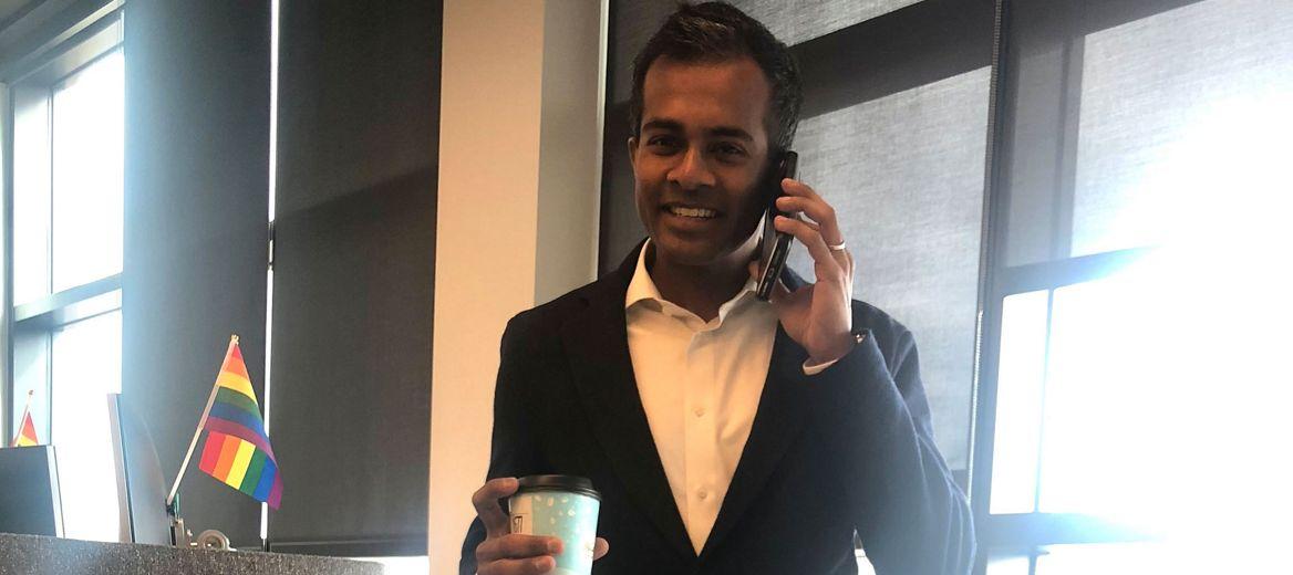 Abiman Rajadurai talking on a cell phone, smiling