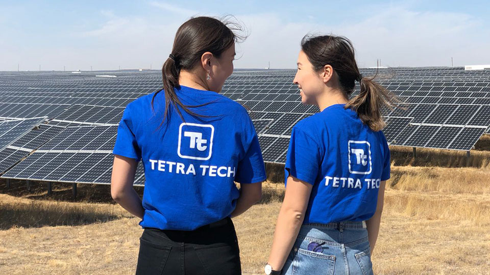 two tetra tech employees standing near solar panels