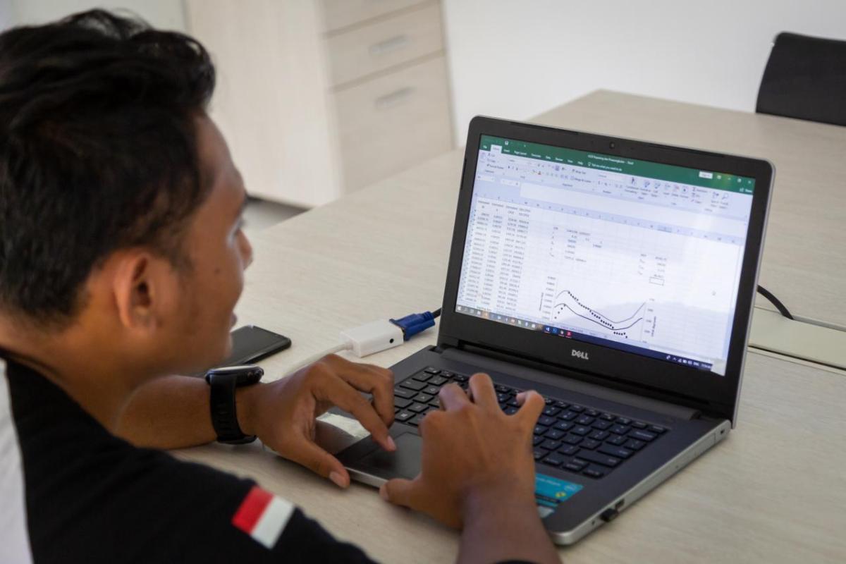 A person looking at a laptop screen. Graphs, spreadsheets visible.
