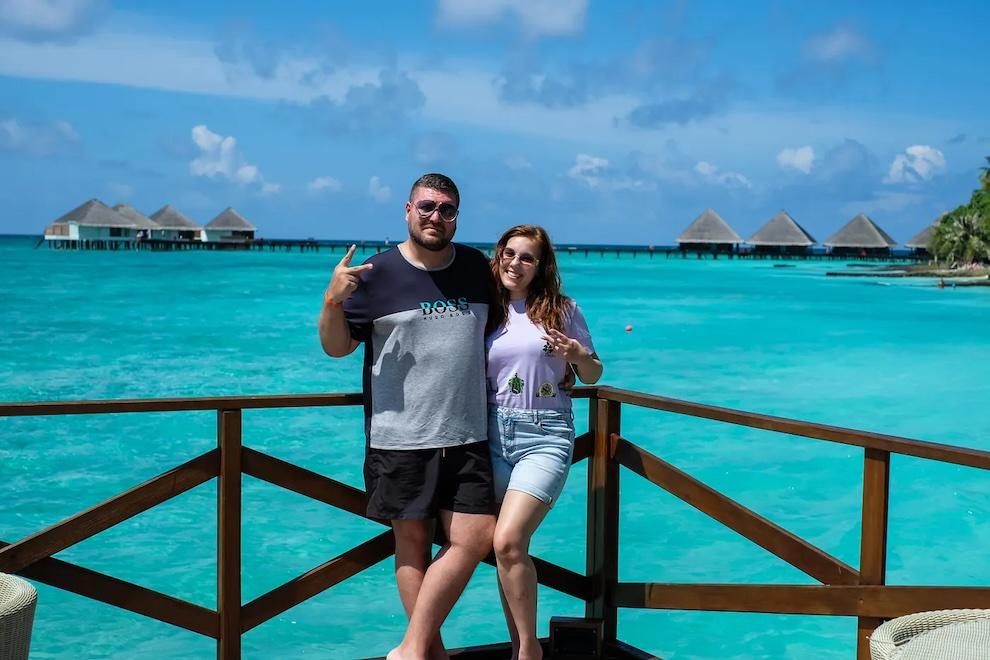 Alexander Ivanov and his wife in front of a beautiful blue ocean.