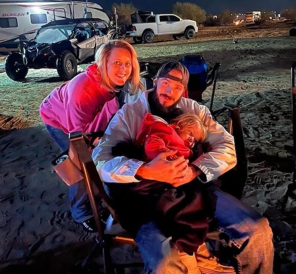 Amber shown with her husband and child at a campfire.