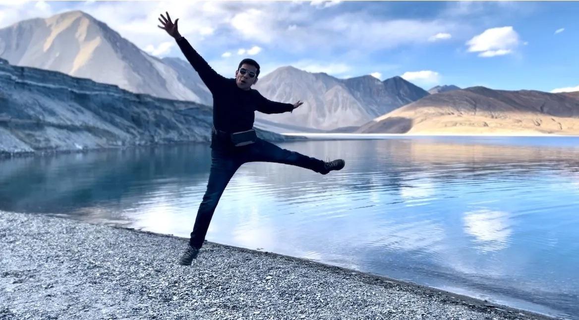 Arpan Gupta leaping in the air in front of a lake.