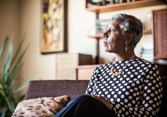 Person sitting on a couch in a living room setting looks towards a window