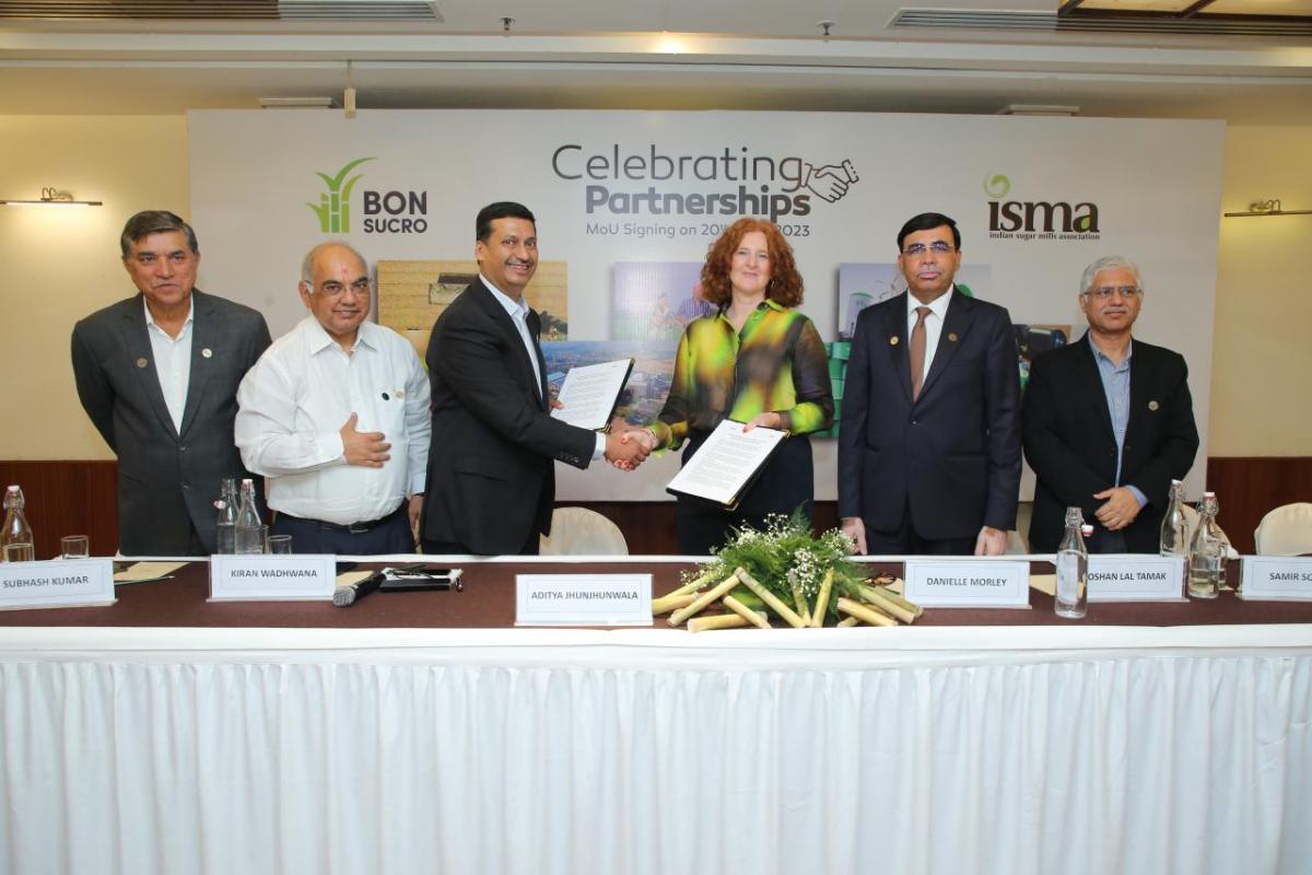 The CEO of Bonsucro and President of ISMA shake hands as they hold the signed MoU. Other participants look on.
